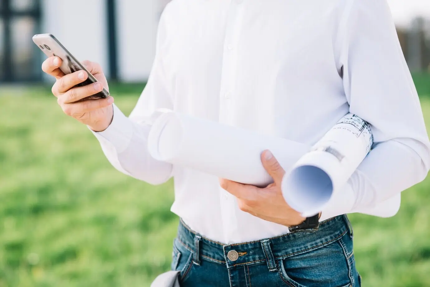 Обрезанный кадр мужчины с чертежами и смартфоном